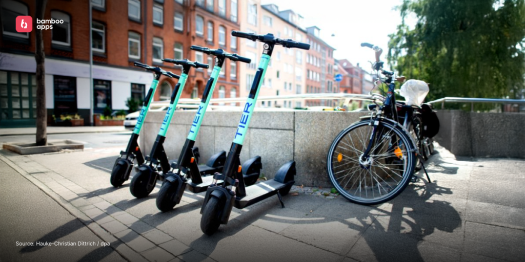 Row of Tier electric scooters parked next to bicycles on a city street